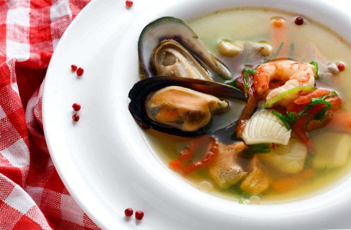 Seafood soup with white fish, shrimp and mussels in a plate garnished with spices