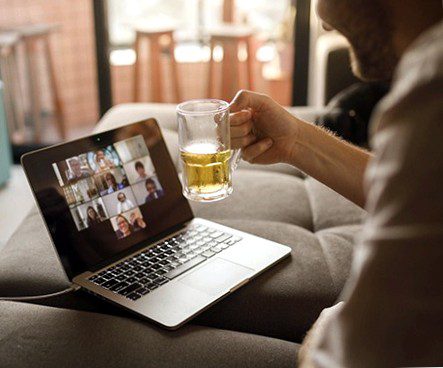Laptop users in a video chat with a beer in hand